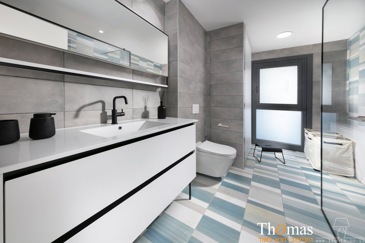 חדר אמבטיה ב גווני אפור וכחול עם תאורה שקועה