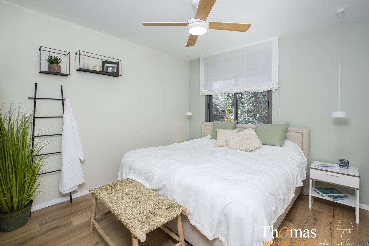 חדר שינה עם מאוור תקרה מאיר בגוון עץ ומנורות קריאה תלויות לצידי המיטה