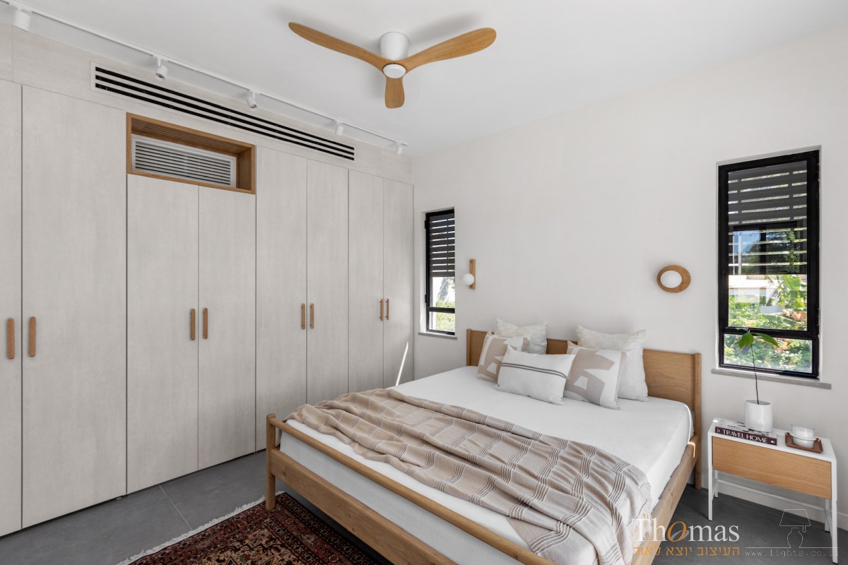 חדר שינה עם מאוורר תקרה עץ ושתי מנורות קיר תואמות